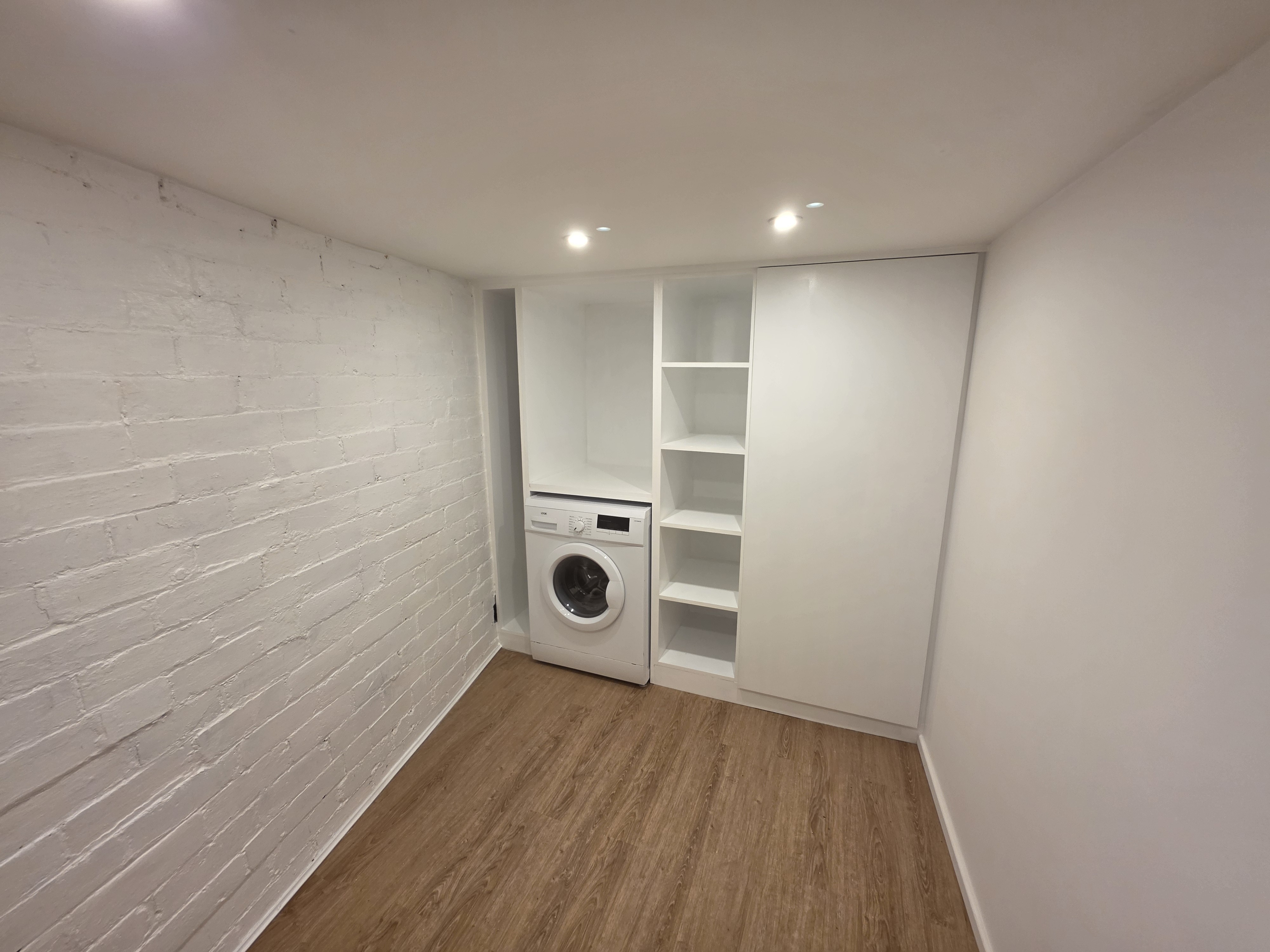Bespoke white fitted utility storage built around washing machine